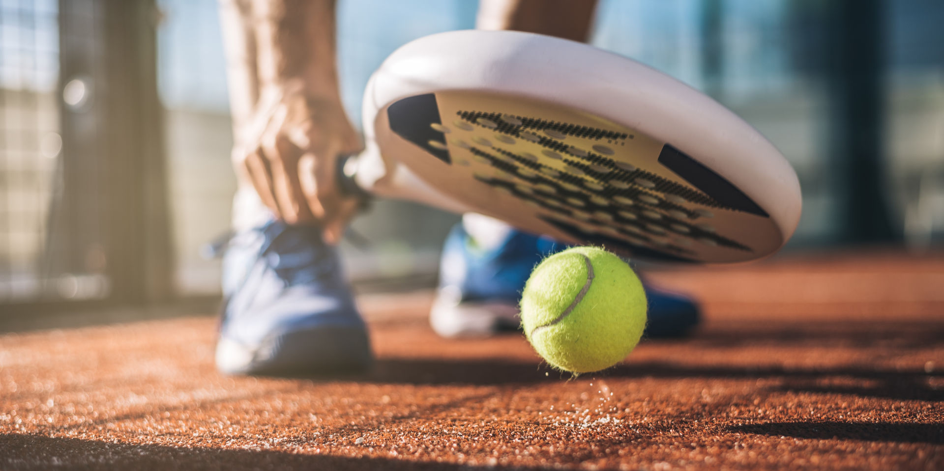 Player bouncing tennis ball with padel racket